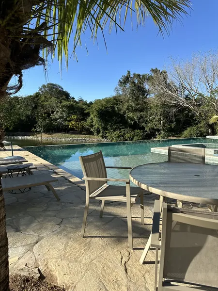 Piscina de borda infinita com deck e mata ao fundo